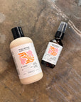 Two bottles of Petal Woods products on a textured surface