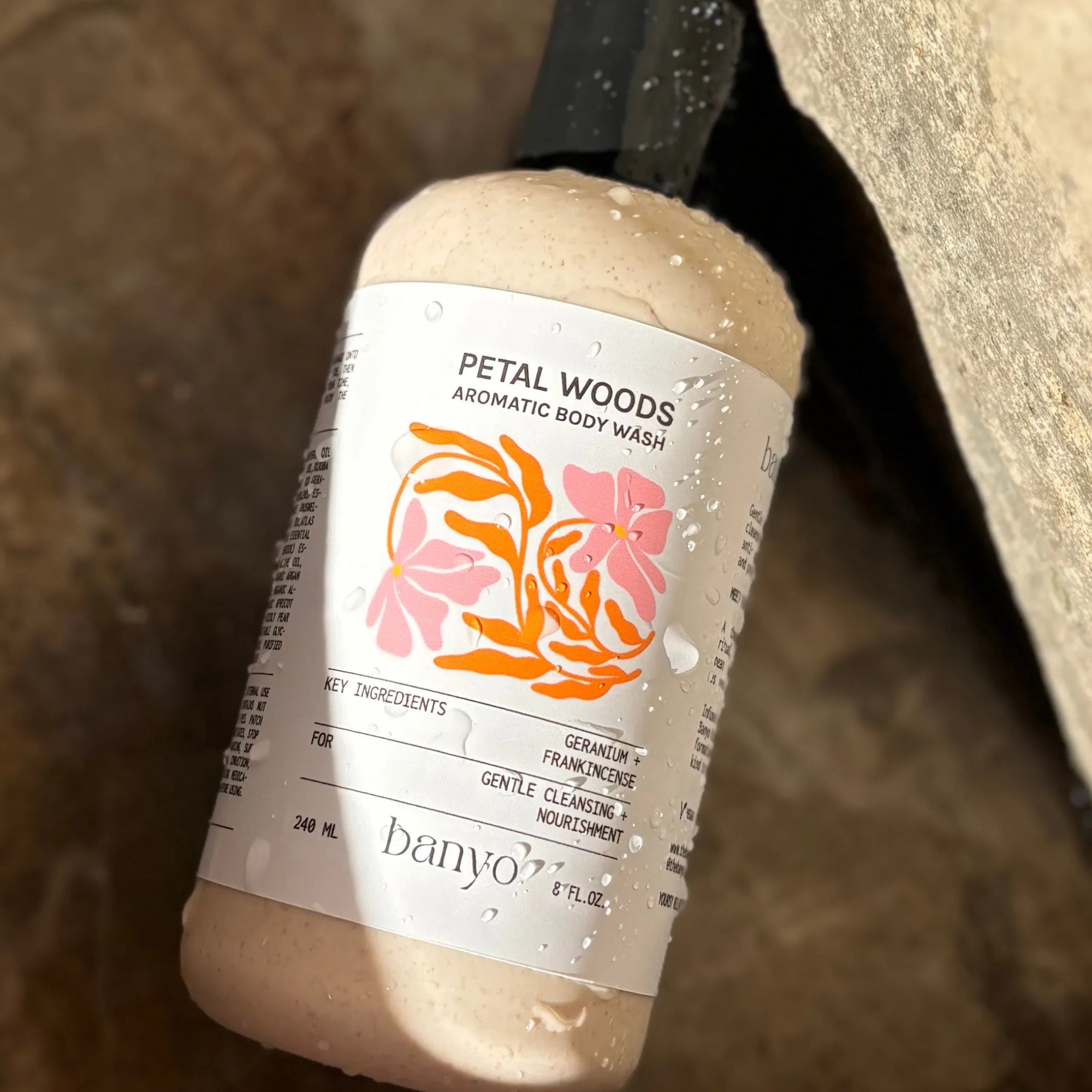 Bottle of banyo Petal Woods Aromatic Body Wash on a stone surface