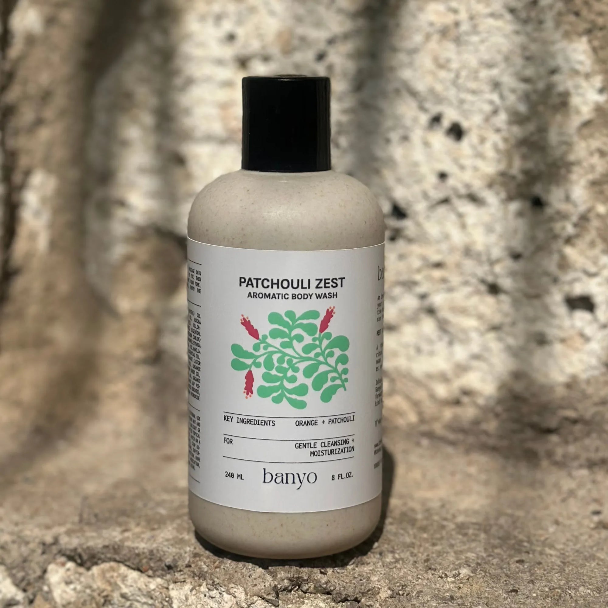 Bottle of Patchouli Zest Aromatic Body Wash by banyo on a stone surface with a natural background
