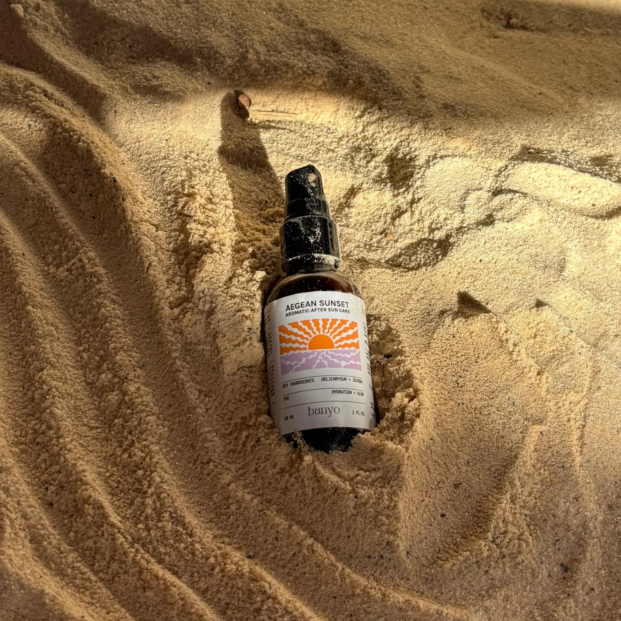 Bottle of Aegean Sunset cologne in sand