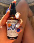 Hand holding a bottle of 'Floral Ocean' mist by banyo with a blurred background