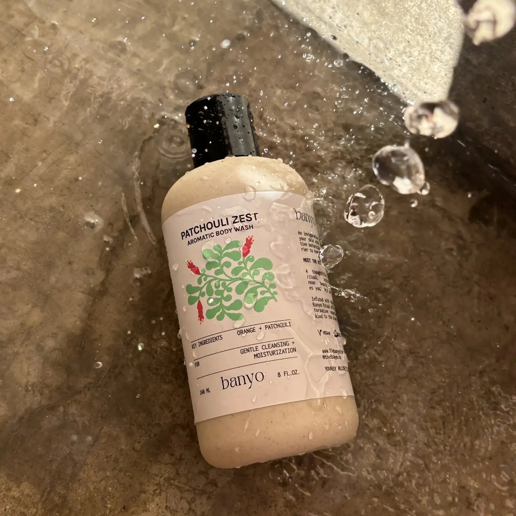 Bottle of banyo Patchouli Zest body wash on a wet surface