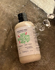 Bottle of banyo Patchouli Zest body wash on a wet surface