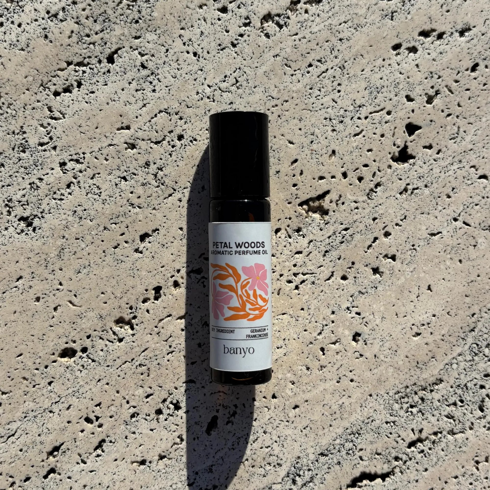 Bottle of 'Petal Woods' aromatic perfume oil by banyo on a textured stone surface