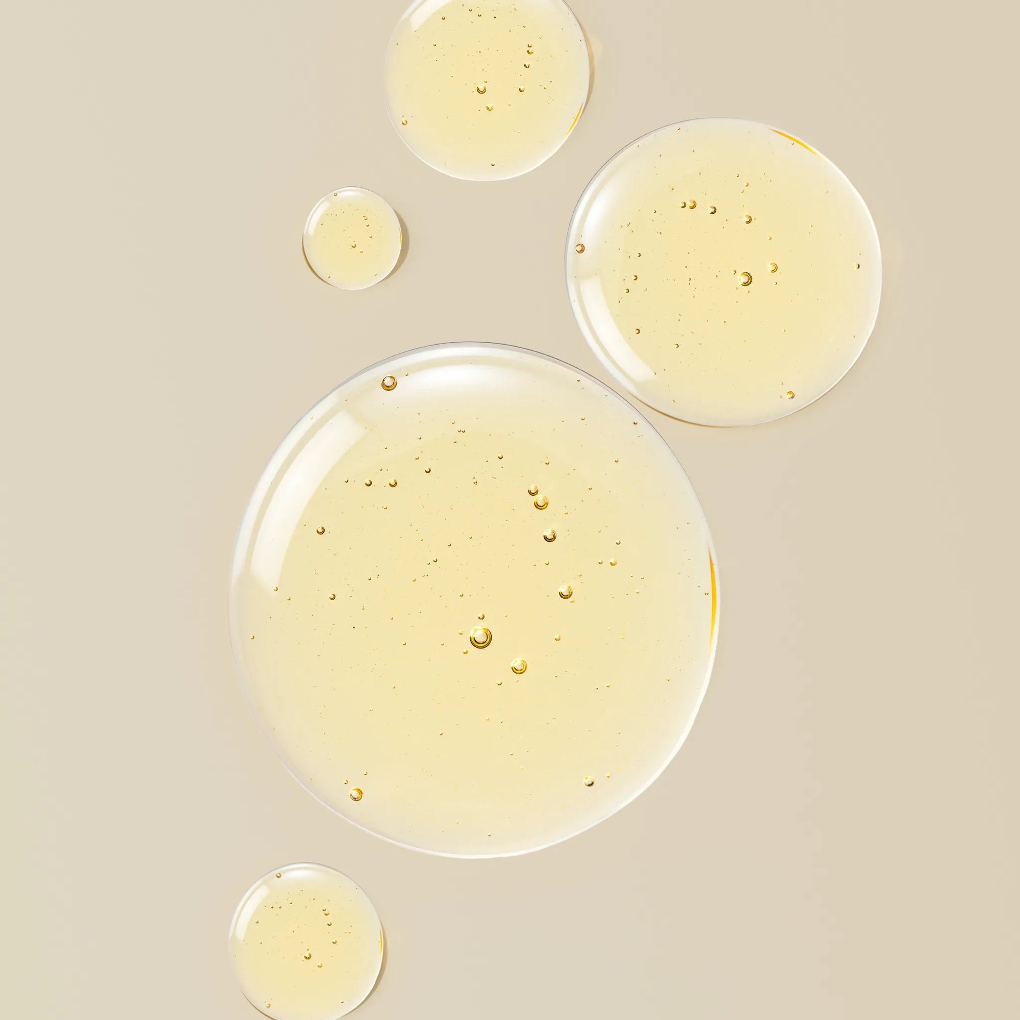 Close-up of transparent liquid droplets on a beige background
