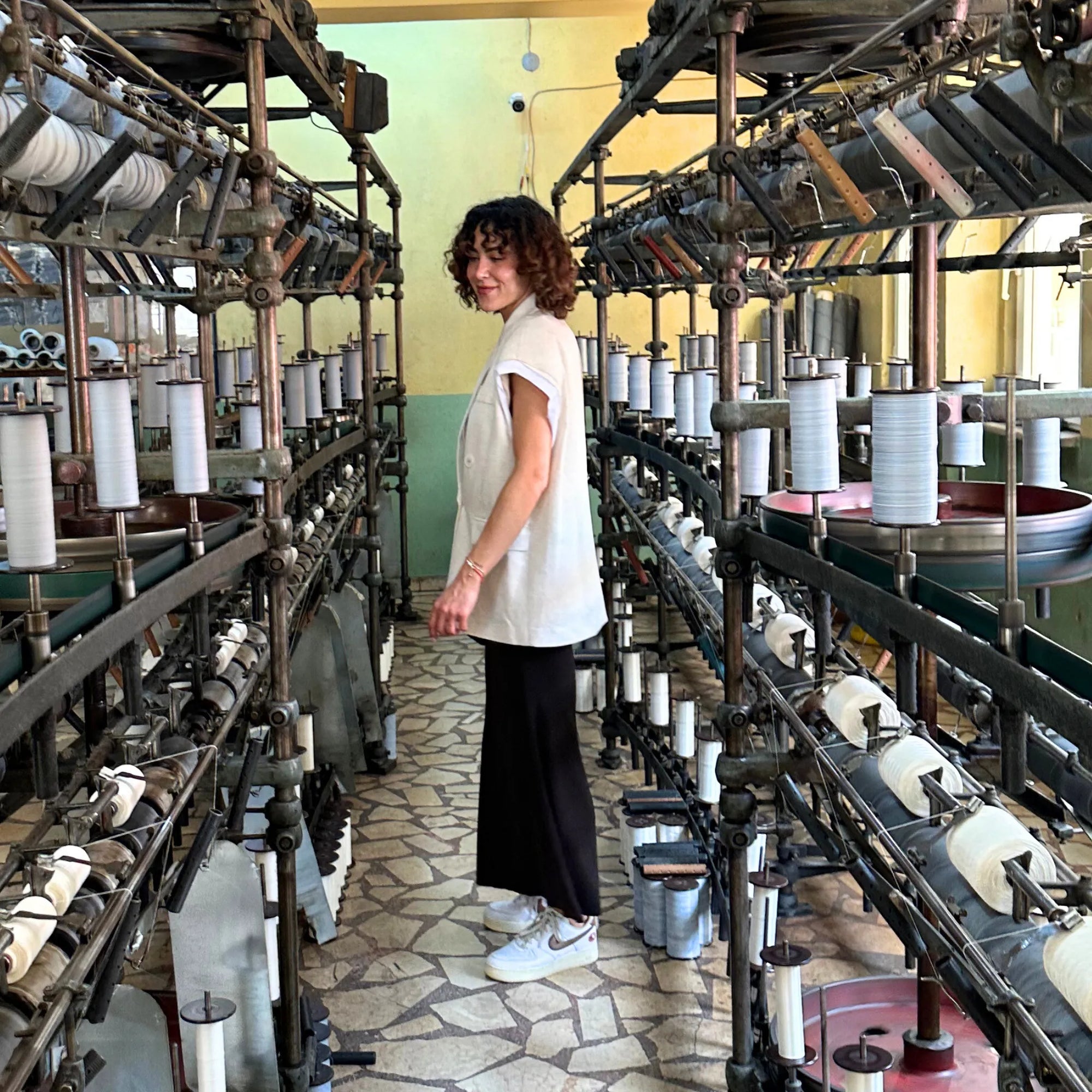 Woman standing in a room with vintage textile machinery